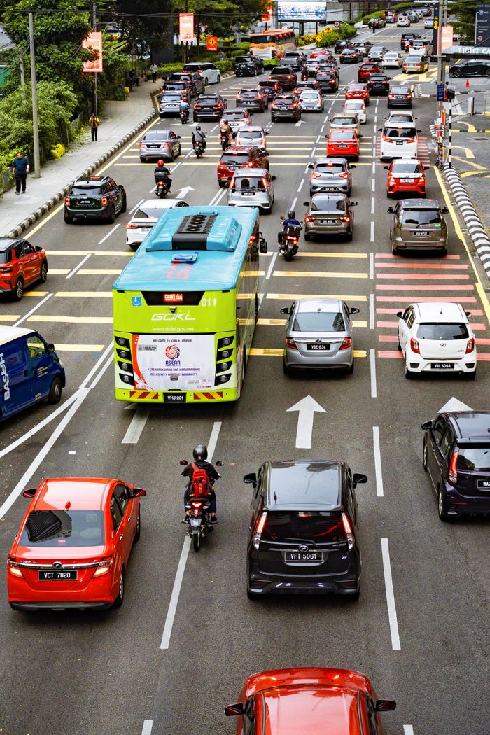 An aerial view of busy street traffic in Kuala Lumpur, Malaysia, featuring cars, motorcycles, and a bus.